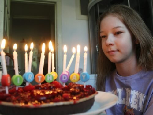 Girl looking at birthday cake with lit candles