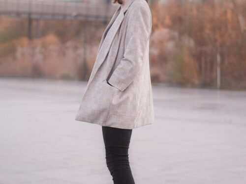 woman in gray coat and black leggings standing on gray concrete floor during daytime