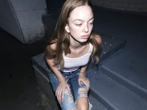 A woman sitting on a ledge with her legs crossed