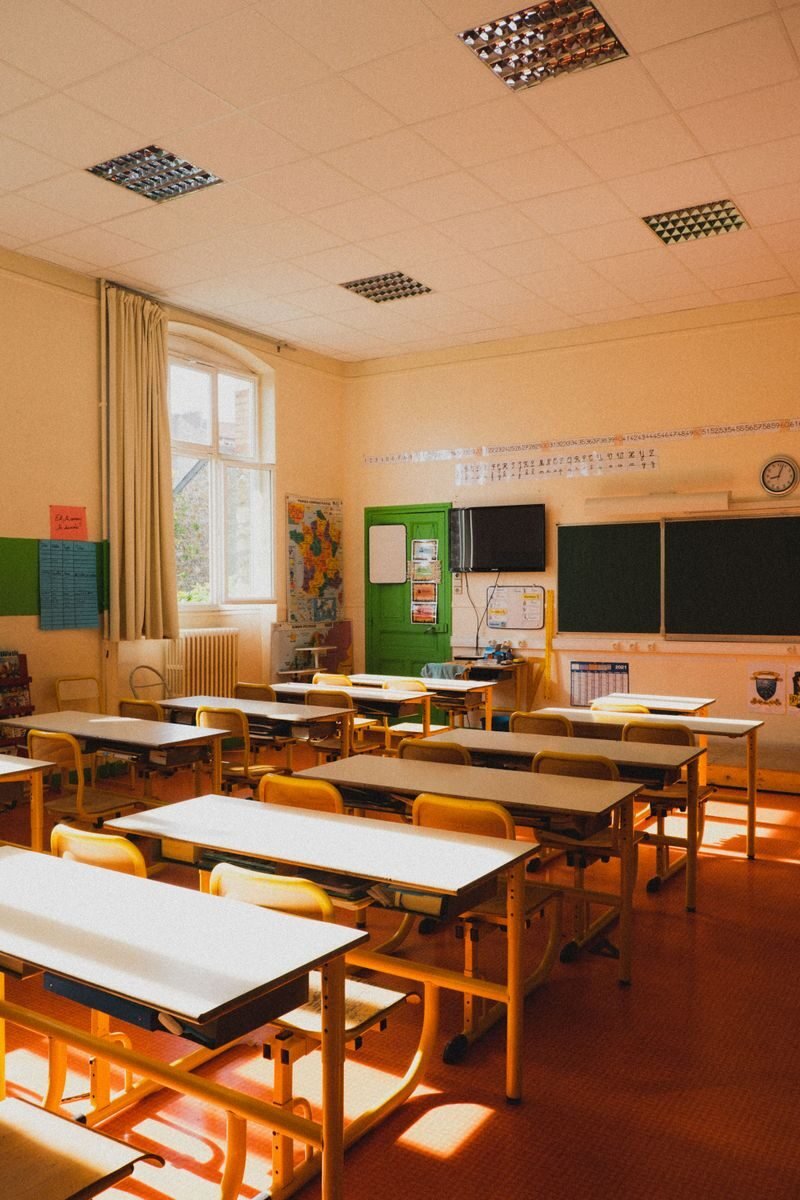 A bright, sunlit empty classroom with tables and chairs in Paris, France.