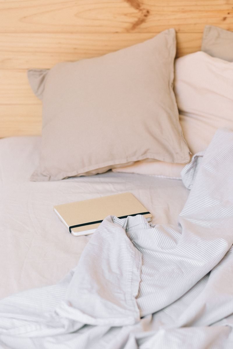 A tranquil bedroom scene with cozy pillows, notebook, and soft bedding.