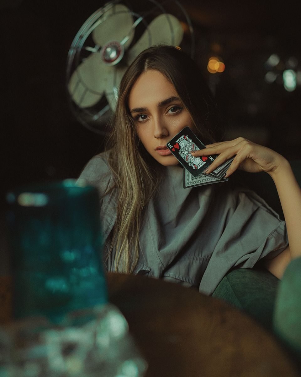 Portrait of a woman in a Moscow cafe holding playing cards with an enigmatic expression.