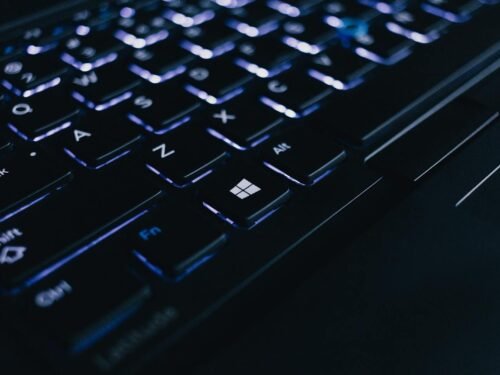 Detailed view of an illuminated laptop keyboard showing individual keys and backlight effect.