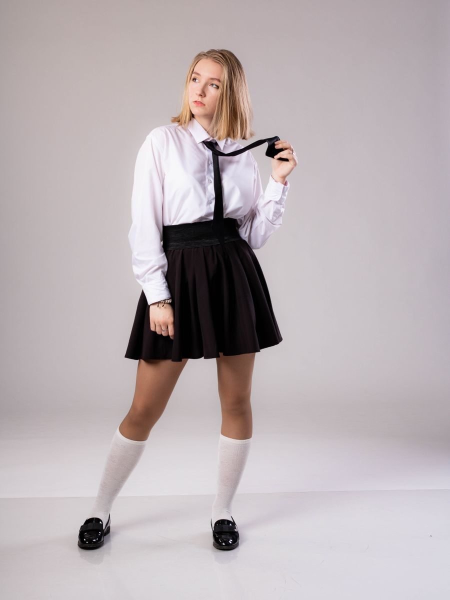 Teen girl in school uniform posing thoughtfully indoors.