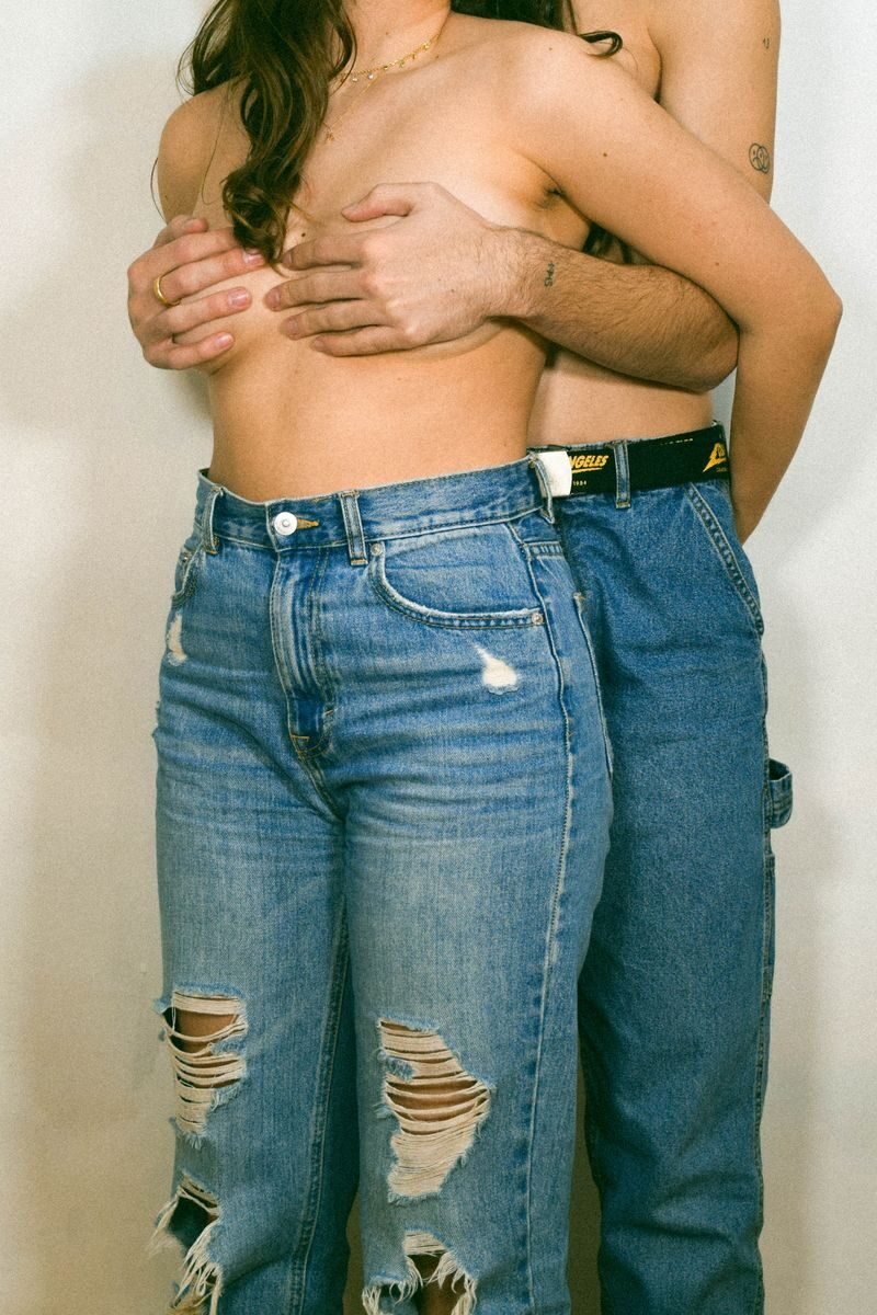 A close-up view of a couple embracing, wearing denim jeans and exuding casual intimacy.