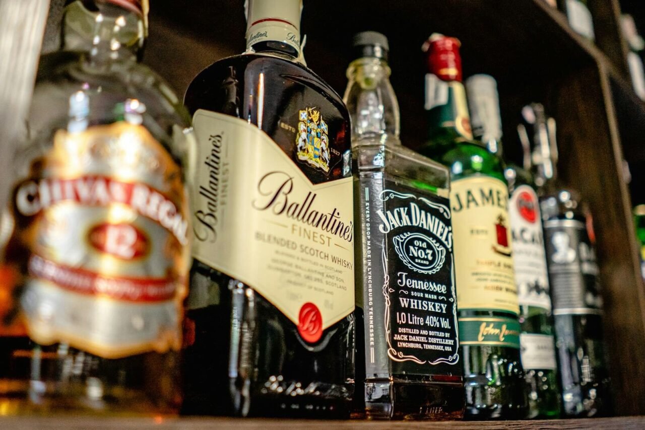 Close-up of various whiskey bottles on a bar shelf showcasing popular brands.