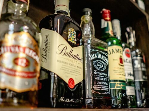 Close-up of various whiskey bottles on a bar shelf showcasing popular brands.