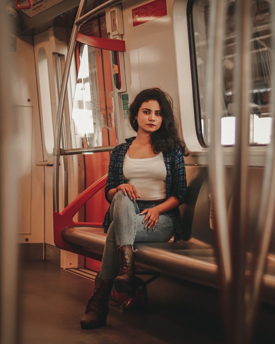 A young woman sits inside a train in Ahmedabad, India, wearing casual attire.