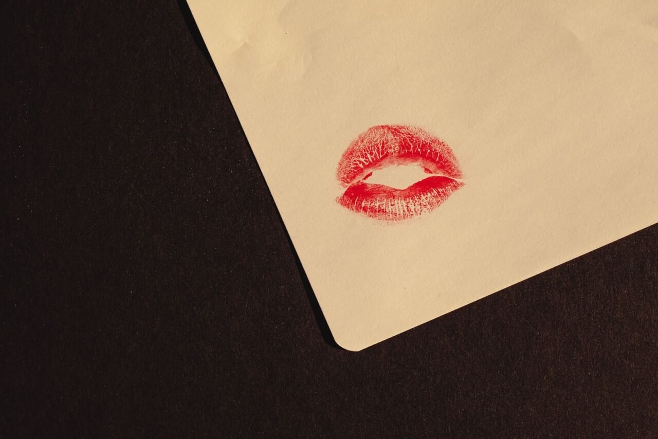 Close-up of a red lipstick kiss imprint on paper with copy space, symbolizing romance and affection.
