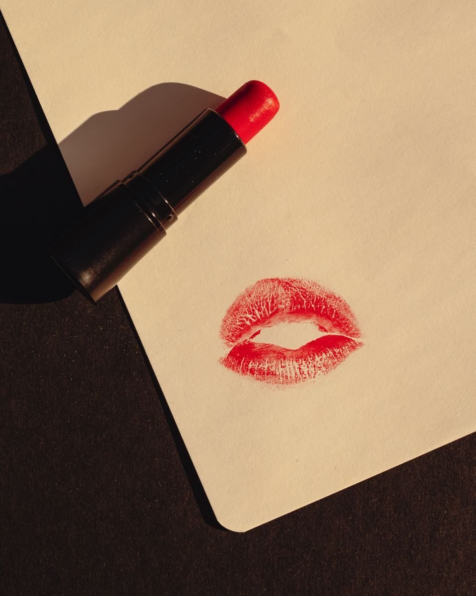 Close-up of a red lipstick and kiss mark on paper against black background. Perfect for beauty and fashion themes.