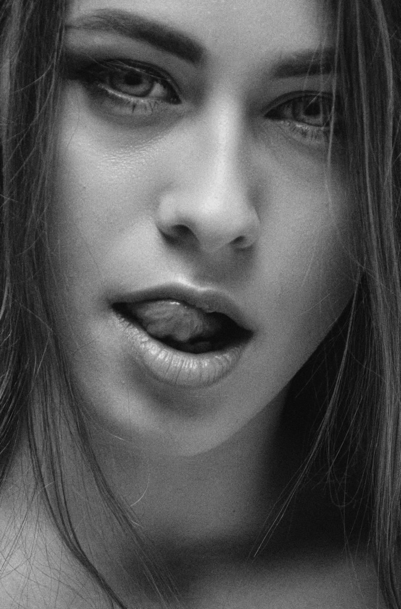 Close-up black and white portrait of a young woman with a playful expression.