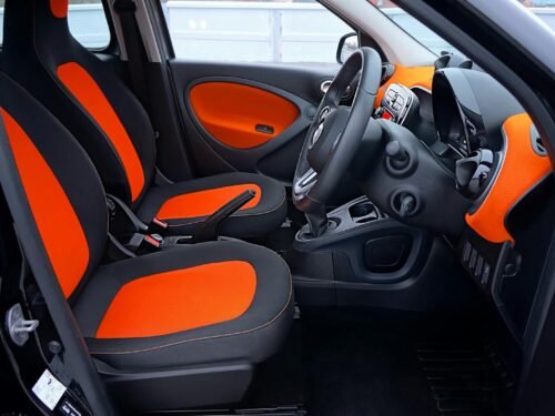 Explore this modern car interior featuring striking orange and black seats with a sleek dashboard.