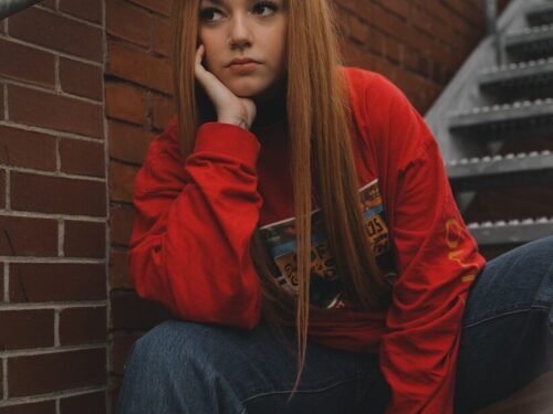 woman in red hoodie and blue denim jeans sitting on stairs