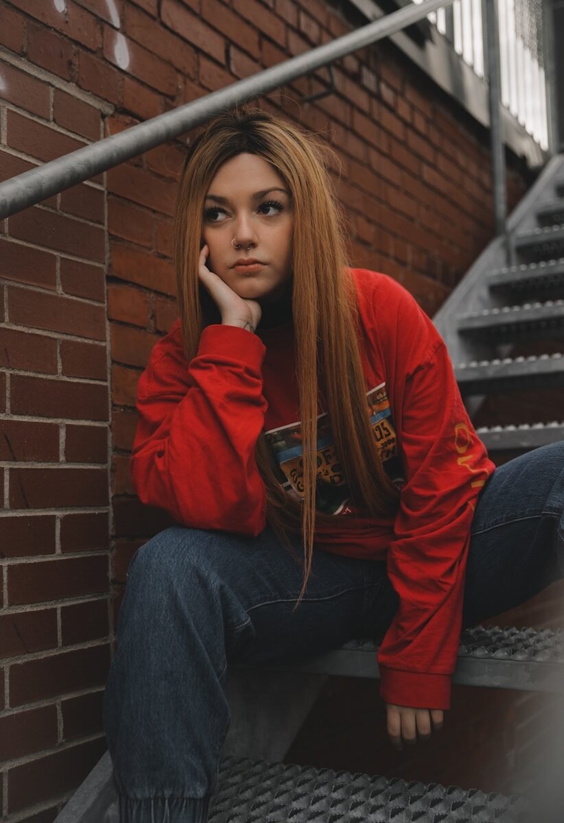 woman in red hoodie and blue denim jeans sitting on stairs