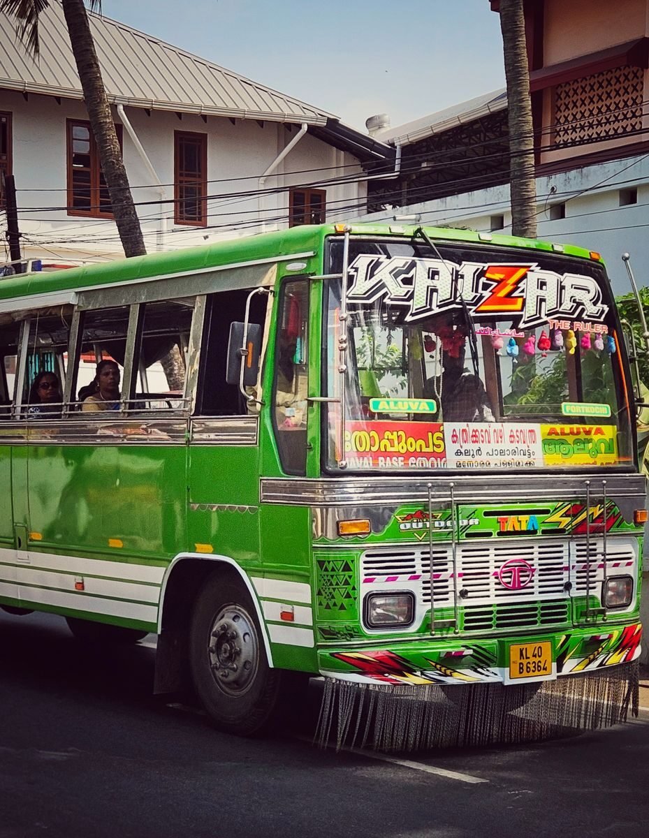 A vibrant green public bus on city streets in Kochi, Kerala, India, showcasing local urban life.