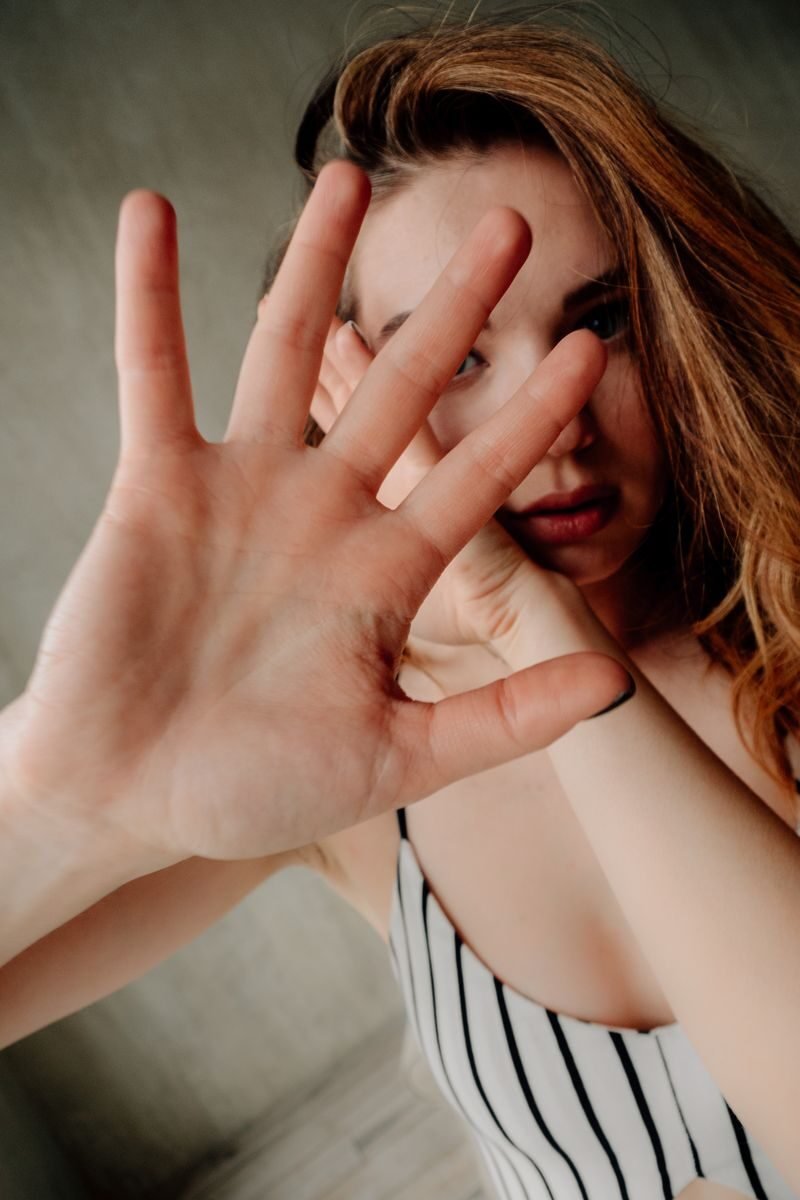 A woman raises her hand in a protective gesture, hints of caution and intimacy.
