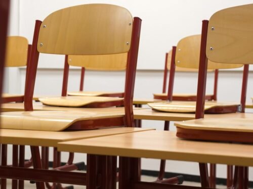 A modern and empty classroom featuring wooden chairs and desks with a focus on education and learning spaces.