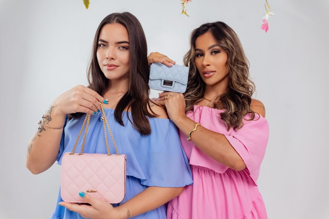 Two women showcasing stylish pastel handbags in a studio setting, emphasizing modern elegance and fashion.