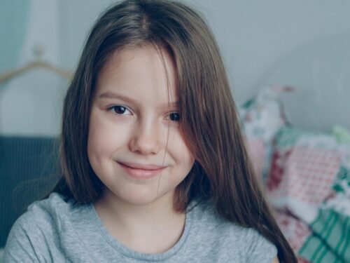 A young girl smiles directly at the camera.