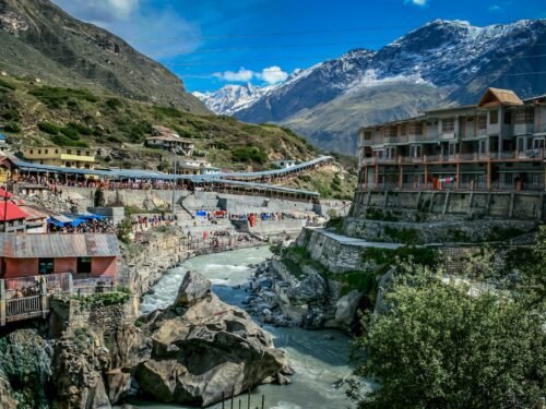 houses near river and mountain under blue sky during daytime