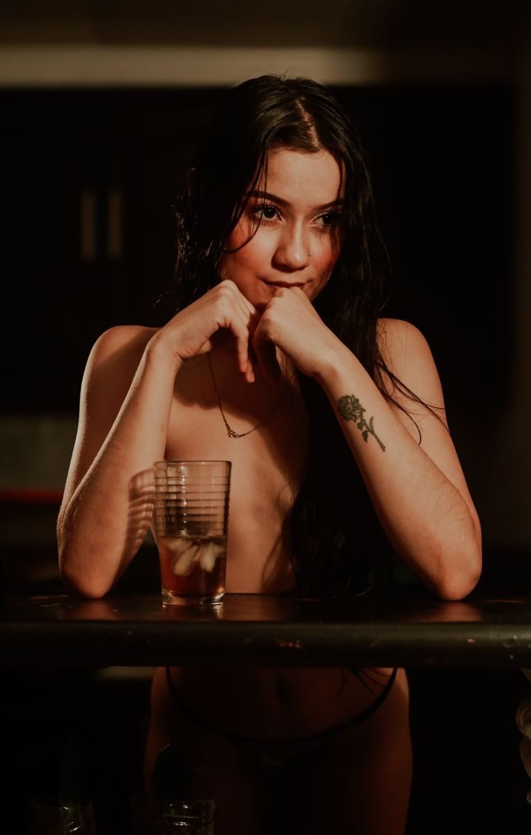Moody portrait of a nude woman captured in warm lighting.