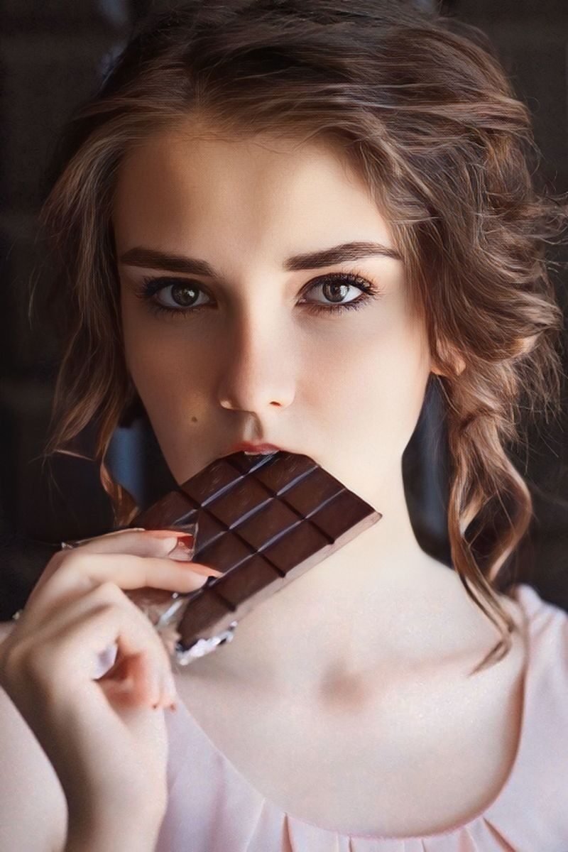 Captivating portrait of a young woman savoring a piece of chocolate