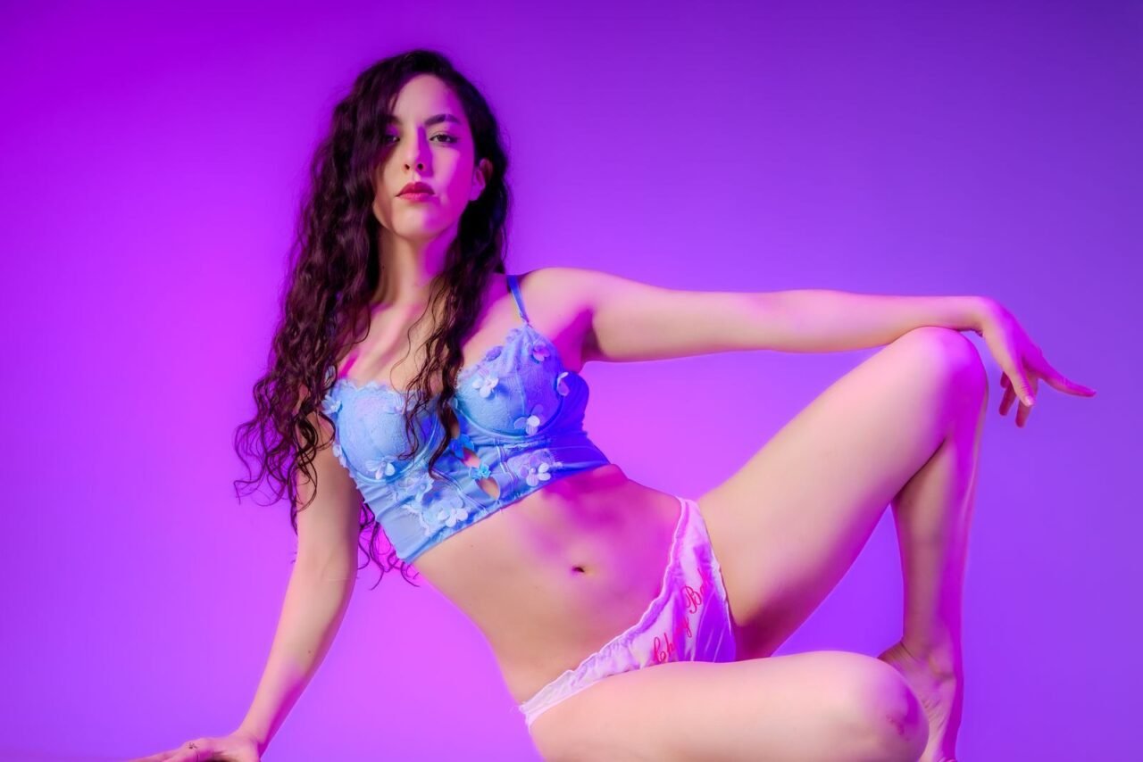 Stylish portrait of a woman posing in colorful lighting, showcasing elegance and creative expression.