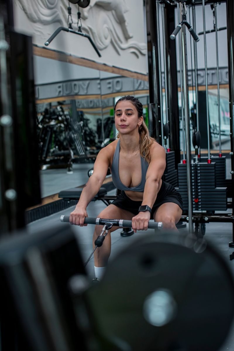 Focused woman working out on a rowing machine in a modern gym setting. Strength and determination.