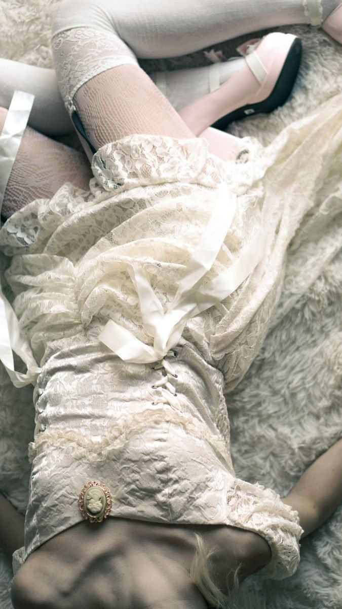 A flat lay of vintage lace fashion with feminine accessories and delicate details on a textured background.