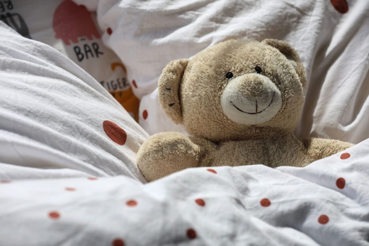 A cozy teddy bear nestled in white polka dot bedding, exuding warmth and comfort.
