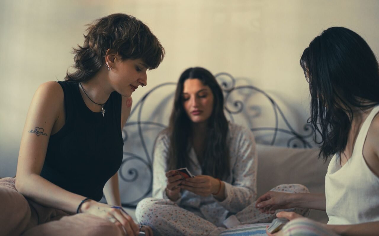 Three women enjoy a card game in a relaxed, cozy indoor setting.