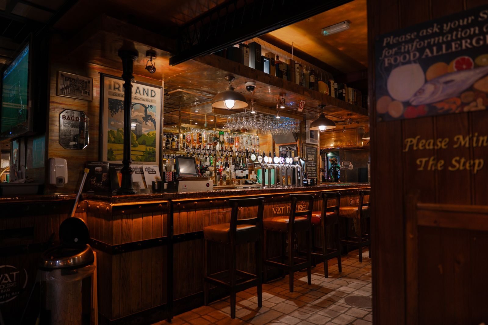 Warm, inviting interior of an Irish pub with a wooden bar counter and stools.