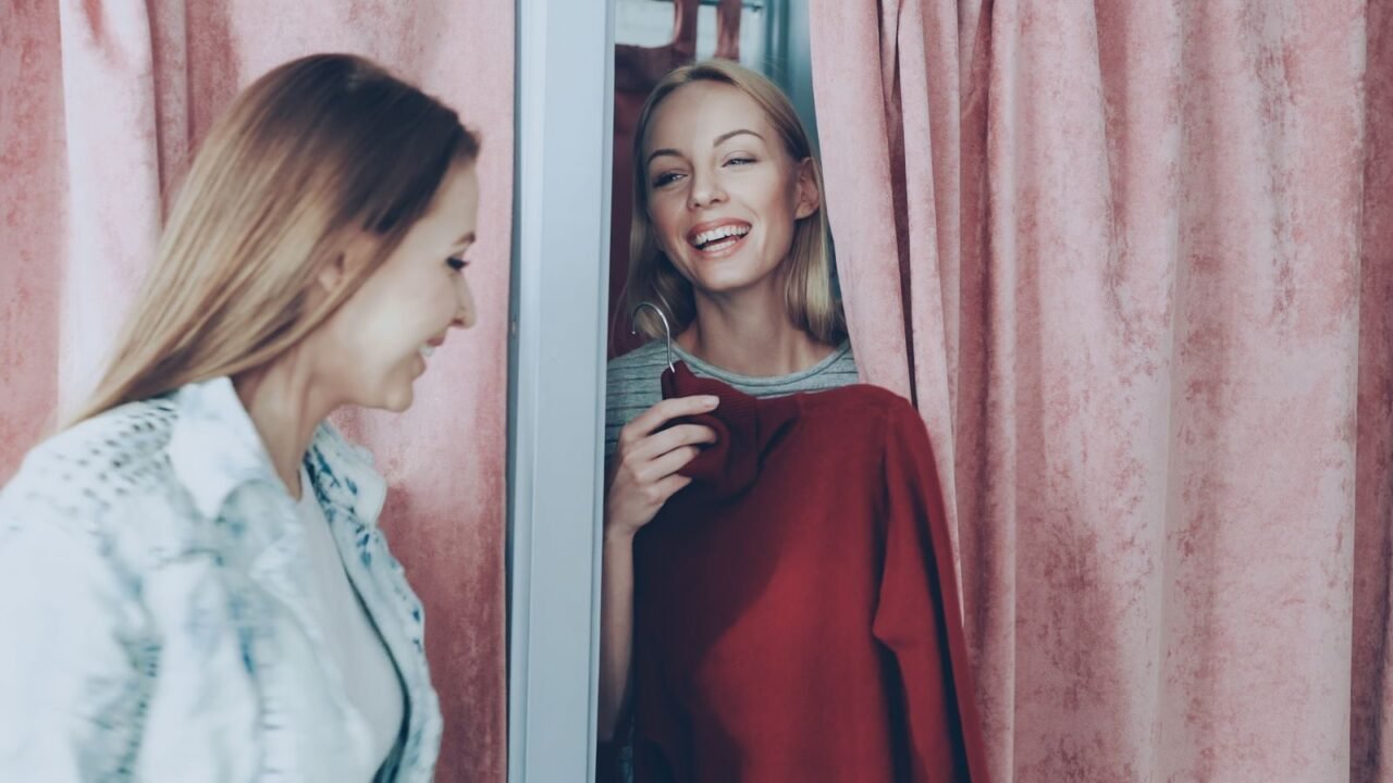 Two women enjoying a shopping experience, smiling in a changing room.