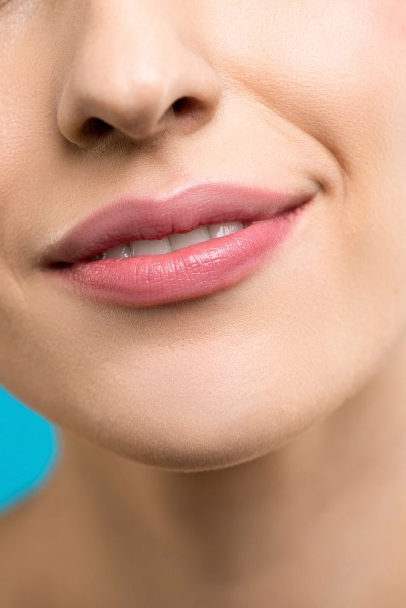 A detailed close-up shot of a woman's smiling lips showcasing smooth skin and lipstick.