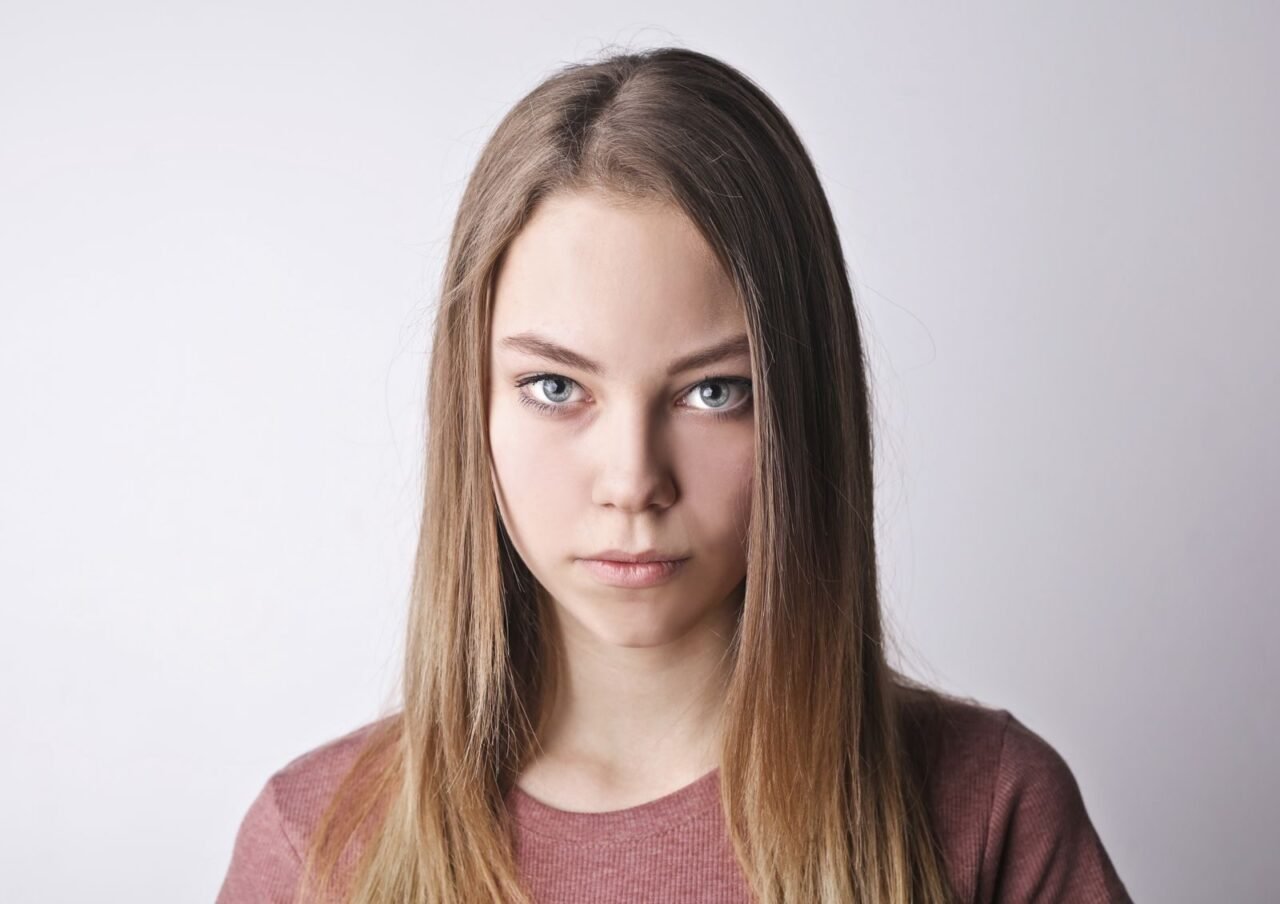 Close-up portrait of a young woman with serious expression against a white background.