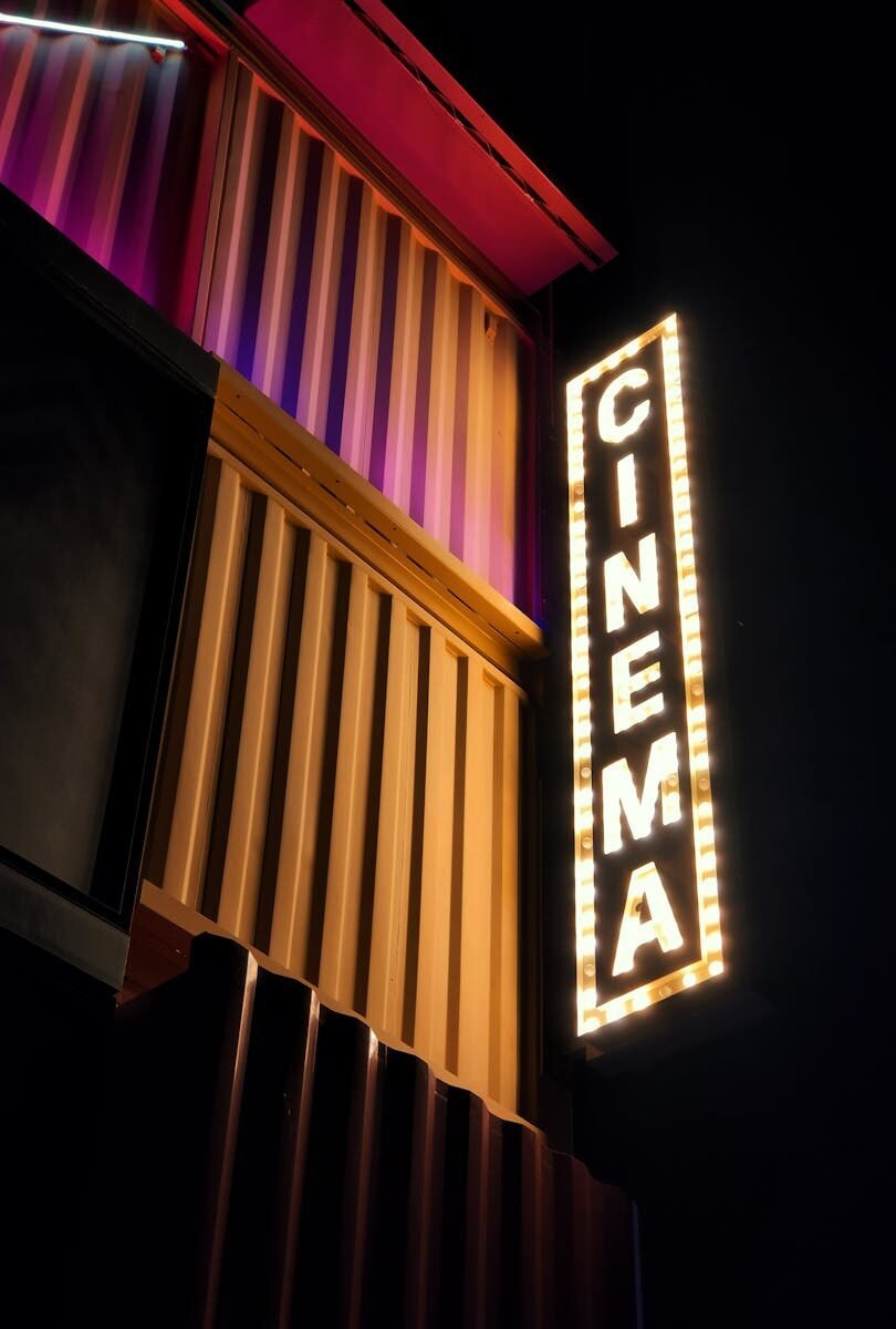 Brightly lit cinema sign against a modern architectural facade in Dubai at night.