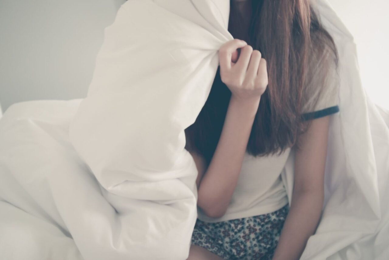 Cozy morning scene with a young woman relaxing under a blanket.