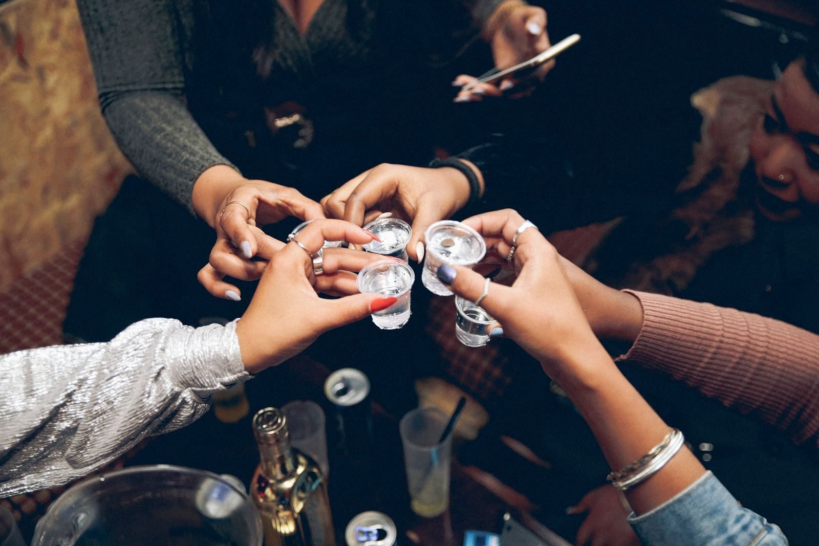 A lively gathering with friends clinking shot glasses, celebrating joy and camaraderie indoors.