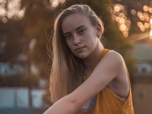 Captivating outdoor portrait of a young woman in a yellow tank top during golden hour.