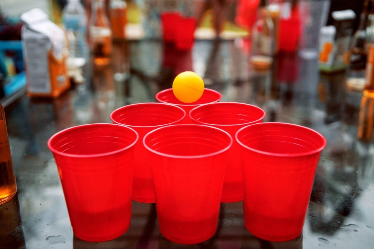 Close-up of red cups and ping pong ball set up for beer pong game at a party.