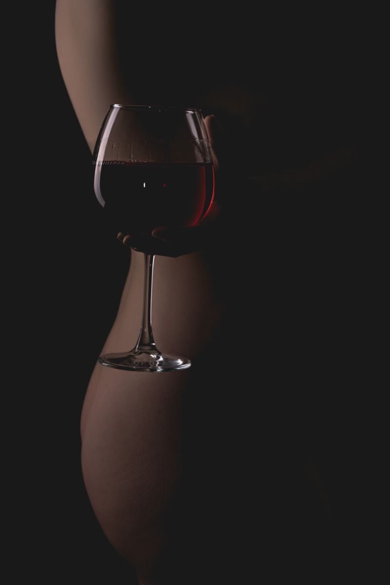 A moody photo of a silhouette holding a wine glass, emphasizing elegance and luxury.