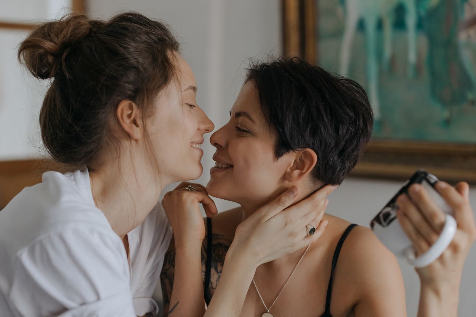 Two women share a tender and loving moment indoors, expressing affection and happiness.