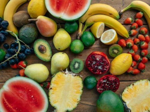 A colorful assortment of fresh fruits including bananas, strawberries, and watermelon arranged on a wooden table.