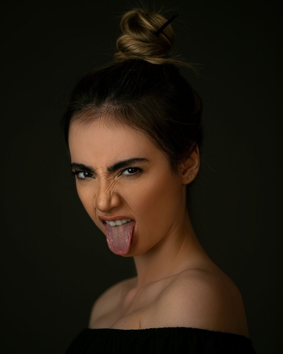 A playful close-up portrait of a woman making a funny expression with tongue out.