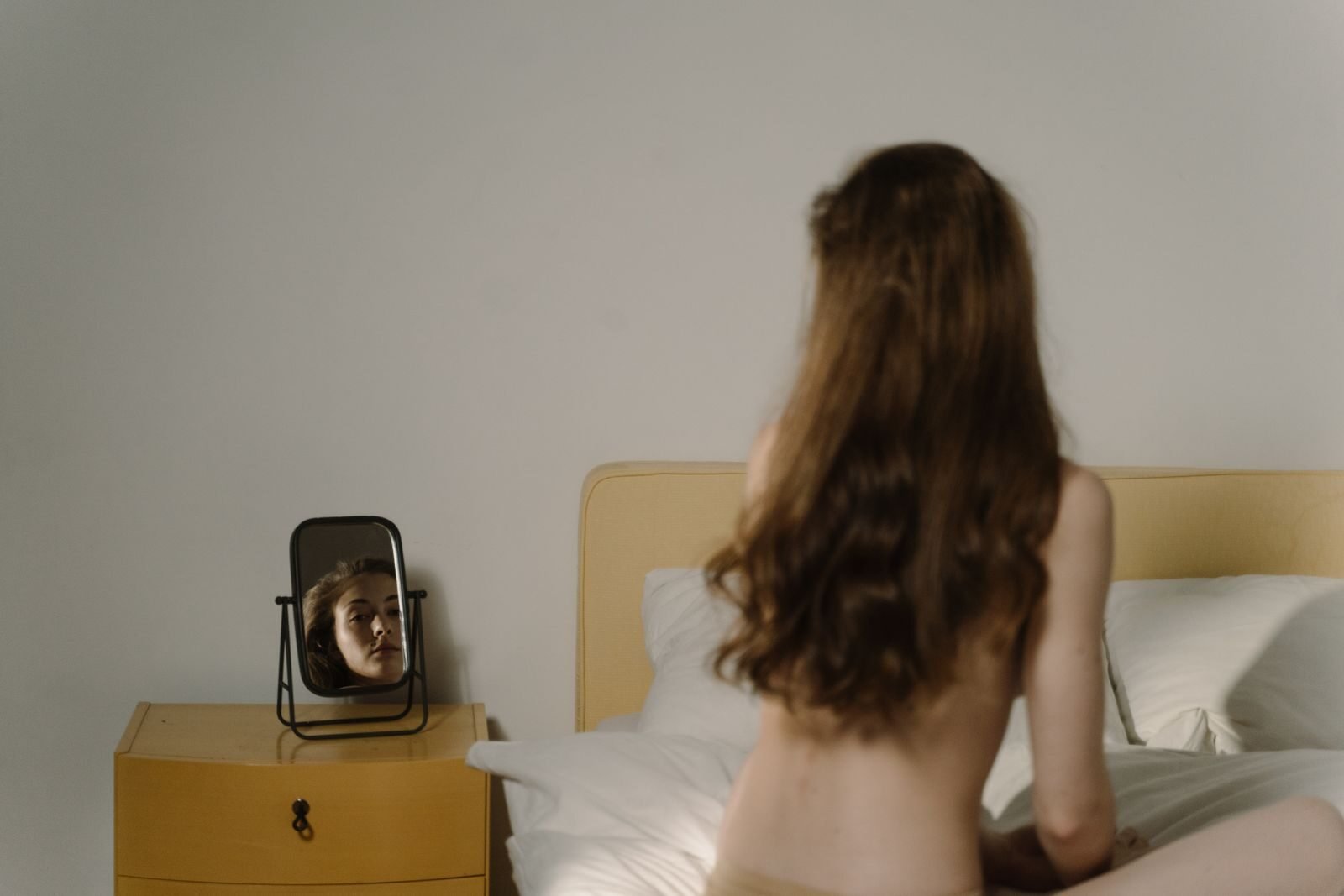 A woman reflects on natural beauty in a bedroom setting with a mirror.