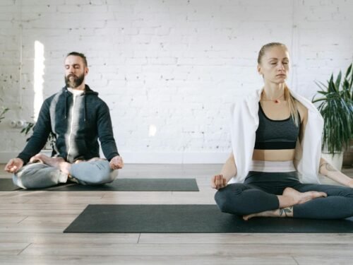 Couple meditating in lotus position in a serene room, enhancing mental peace.
