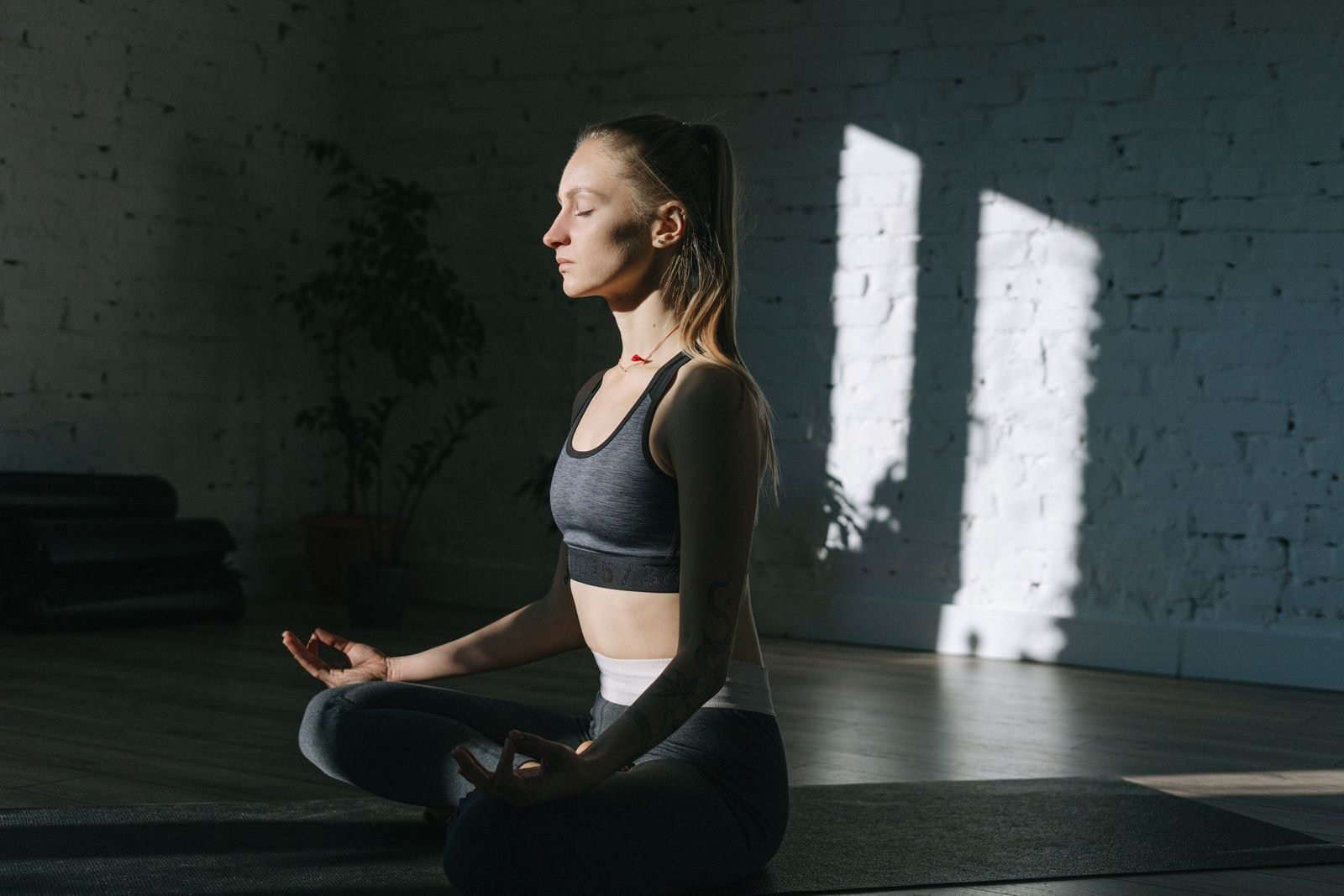 Woman in lotus position meditating indoors, embracing mindfulness and tranquility.
