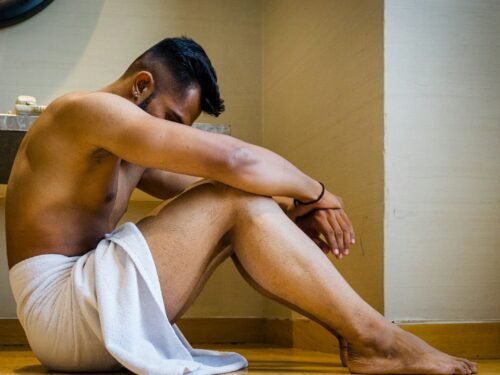 a man sitting on the floor in a bathroom