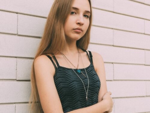 woman in black and white stripe tank top leaning on white wall