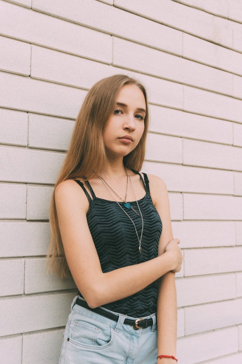 woman in black and white stripe tank top leaning on white wall